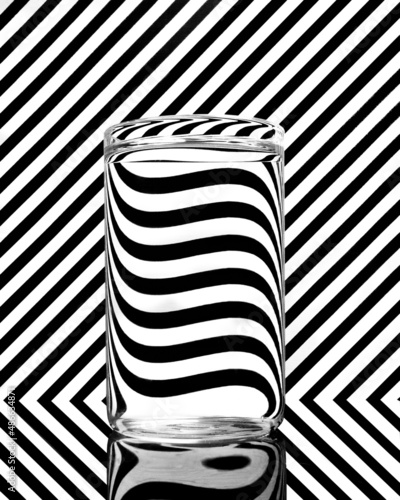 A glass filled with water with a black and white pattern background photo