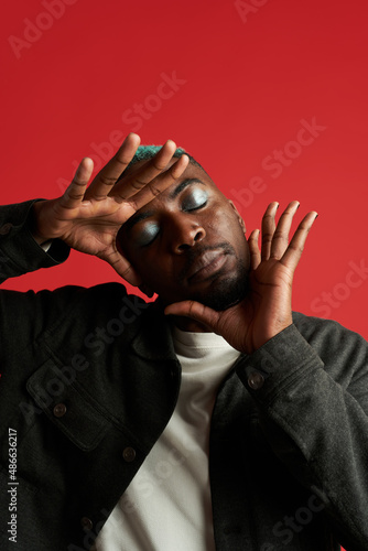 Eccentric black man with makeup in bright studio photo