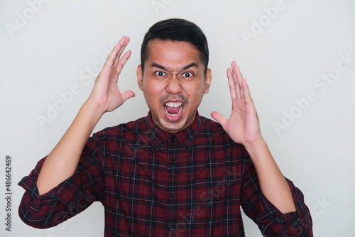 Closeup portrait of adult Asian man showing crazy stressed expression photo