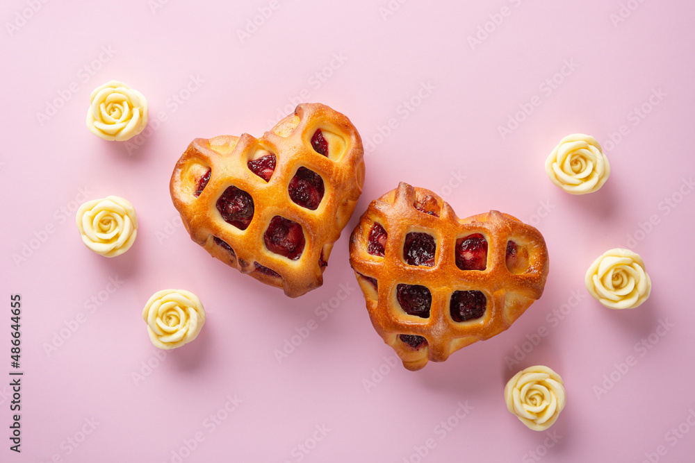 Valentines Day concept. Two heart buns with berry jam and lattice crust on a pink background with white chocolate roses. Top view, close-up, flat lay Valentines Day concept. Two heart buns with berry jam and lattice crust on a pink background with white chocolate roses. Top view, close-up, flat lay