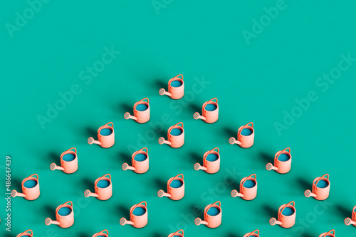 Pink watering can on green background with copy space