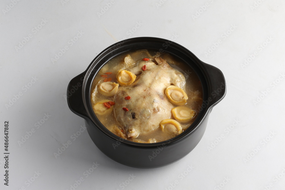 freshly hot stewed whole kampong chicken with abalone seafood in clay pot herbal soup on white background freshly hot stewed whole kampong chicken with abalone seafood in clay pot herbal soup on white background