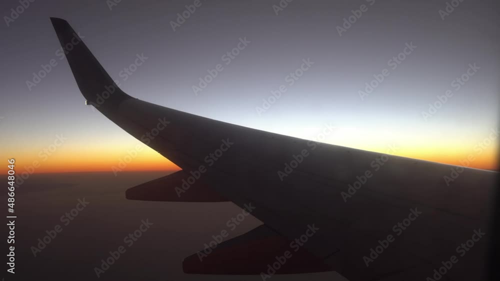 Wing of airplane at sunrise blocks out the sunlight. View from the window of the plane. Aircraft flight on sunset. Traveling by air. Wing of airplane at sunrise blocks out the sunlight. View from the window of the plane. Aircraft flight on sunset. Traveling by air.