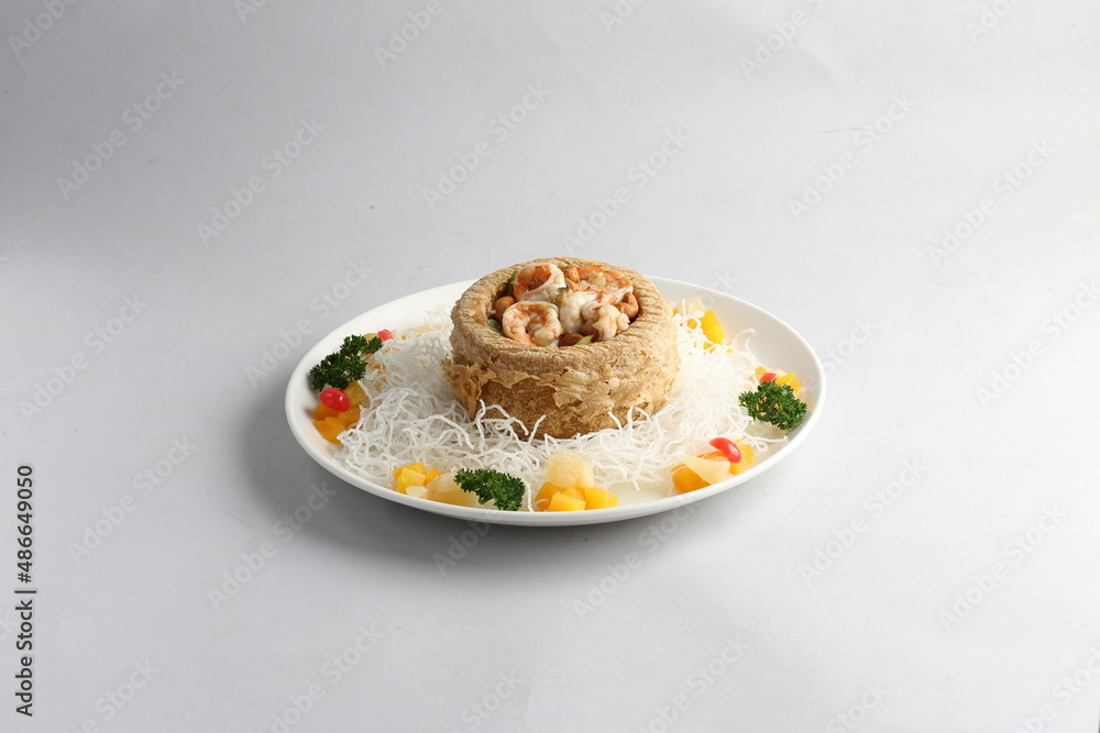 deep fried crispy yam ring with stir fried seafood meat vegetable and cashew nut in sauce and white vermicelli on white background chinese banquet menu