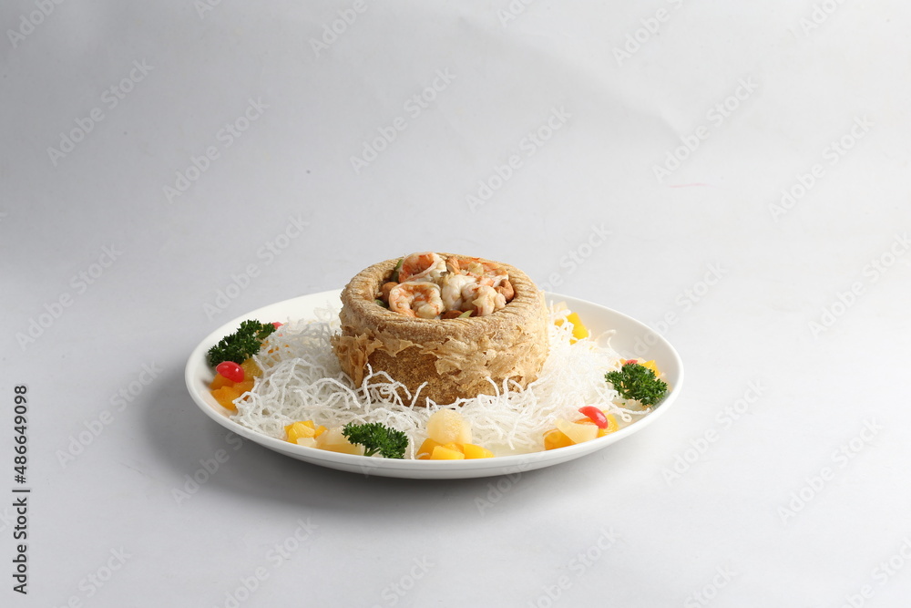 deep fried crispy yam ring with stir fried seafood meat vegetable and cashew nut in sauce and white vermicelli on white background chinese banquet menu
