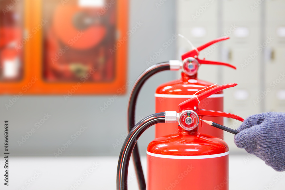 Fire extinguisher has hand engineer inspection checking pressure gauges to prepare fire equipment for protection and prevent emergency and safety rescue and alarm system training concept. Fire extinguisher has hand engineer inspection checking pressure gauges to prepare fire equipment for protection and prevent emergency and safety rescue and alarm system training concept.