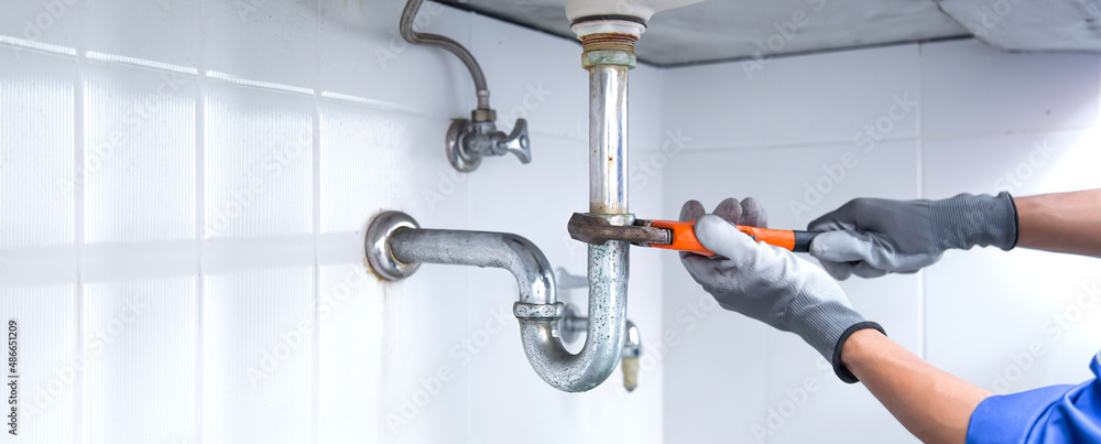 Technician Plumber Using A Wrench To