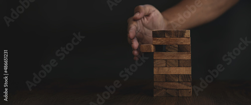 Close-up hands prevent tower stacked with caution to prevent collapse or crash concepts of financial risk management and strategic planning.