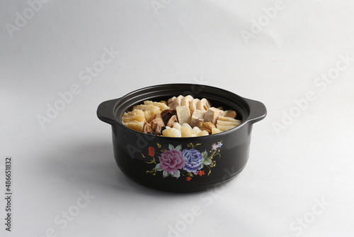 freshly hot stewed Peng cai with  seafood and meat in herbal sauce clay pot and yellow cover on white background Chinese traditional menu photo