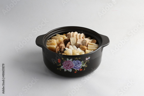 freshly hot stewed Peng cai with  seafood and meat in herbal sauce clay pot and yellow cover on white background Chinese traditional menu photo