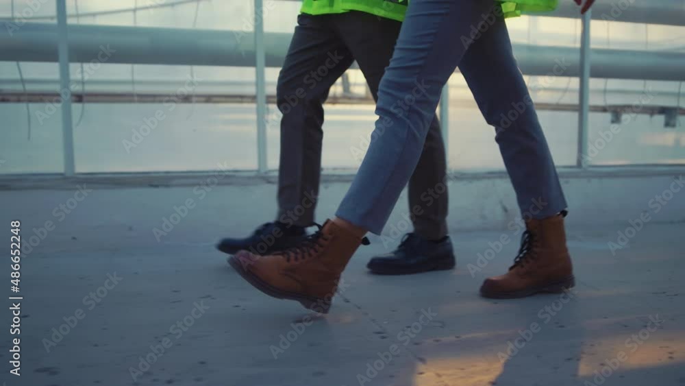 Factory engineers legs walking in modern greenhouse wearing green uniform Factory engineers legs walking in modern greenhouse wearing green uniform