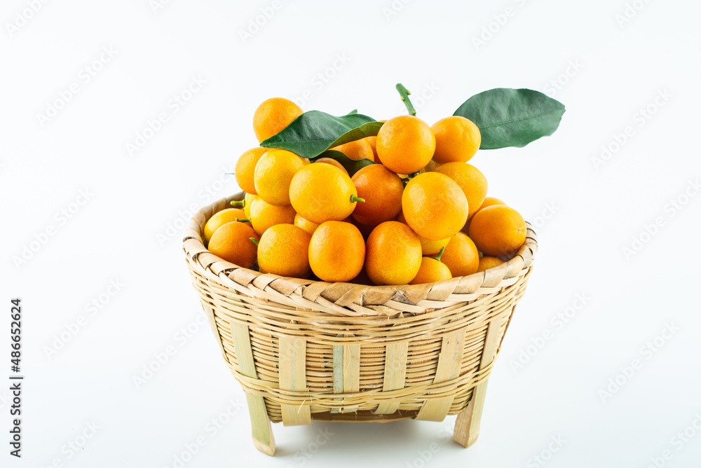 Bamboo basket full of fresh kumquats on white background Bamboo basket full of fresh kumquats on white background