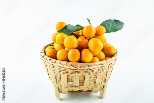 Bamboo basket full of fresh kumquats on white background
