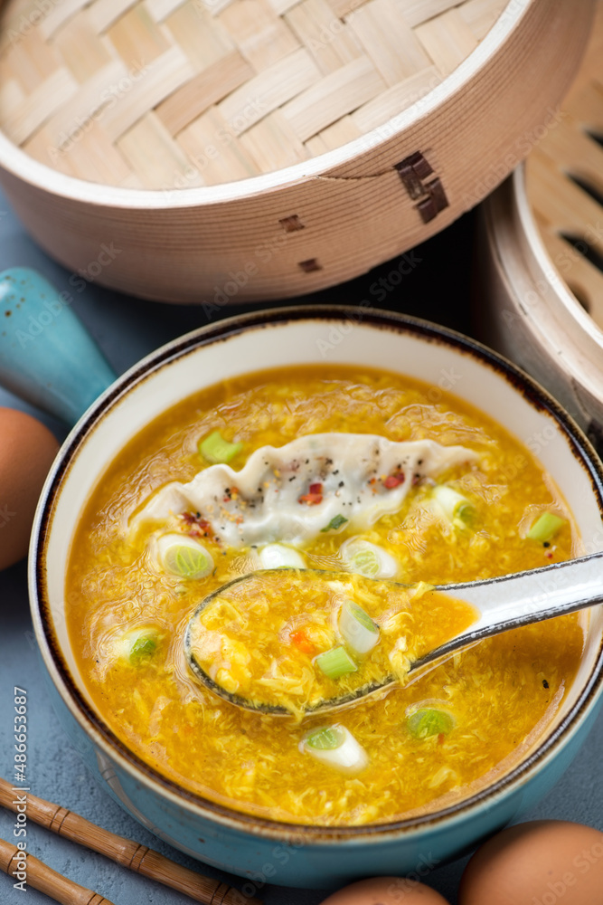 Bowl of chinese traditional egg-drop soup with dumpling and scallions, vertical shot, middle close-up Bowl of chinese traditional egg-drop soup with dumpling and scallions, vertical shot, middle close-up