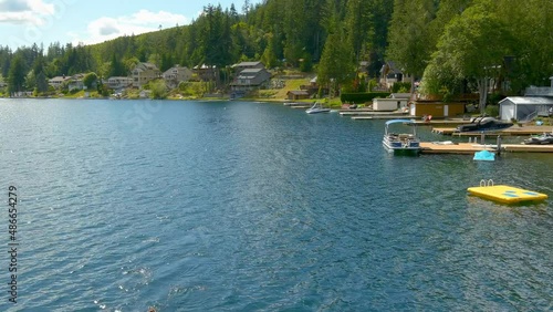 Rising aerial view of a lakeside community as a young woman with her dog navigates calm water with a kayak