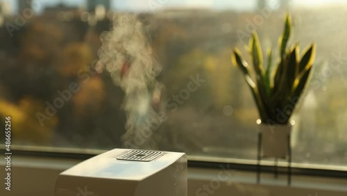 Air humidifier making hot steam to increase humidity at home during dry winter weather. Indoor steam humidifier in living room for better indoor climate environment photo