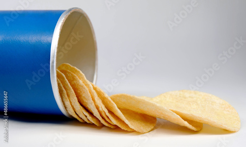 Potato chips are poured out of a can of chips.