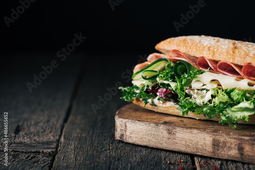 homemade sandwich with ham, cheese and lettuce on a rustic wooden board, selective focus, copy space