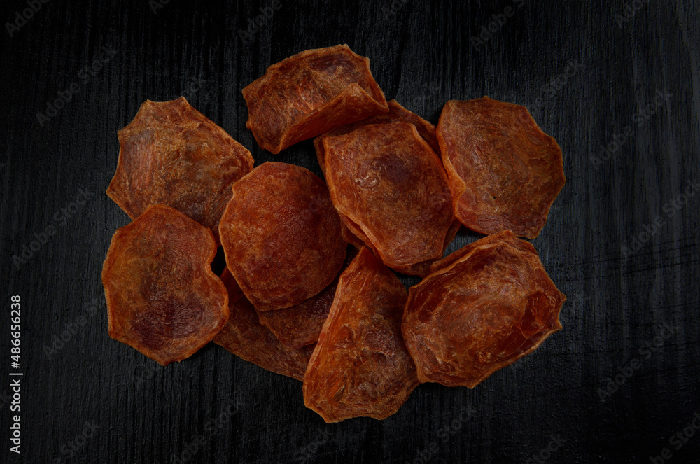 Meat chips on a black background. Beautiful placer of thin slices of dried meat.