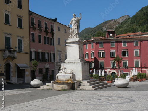 Alberica square in Carrara surrounded by colorful buildings and with the statue dedicated to Beatrice Este made of marble and the lion fountain in the center photo