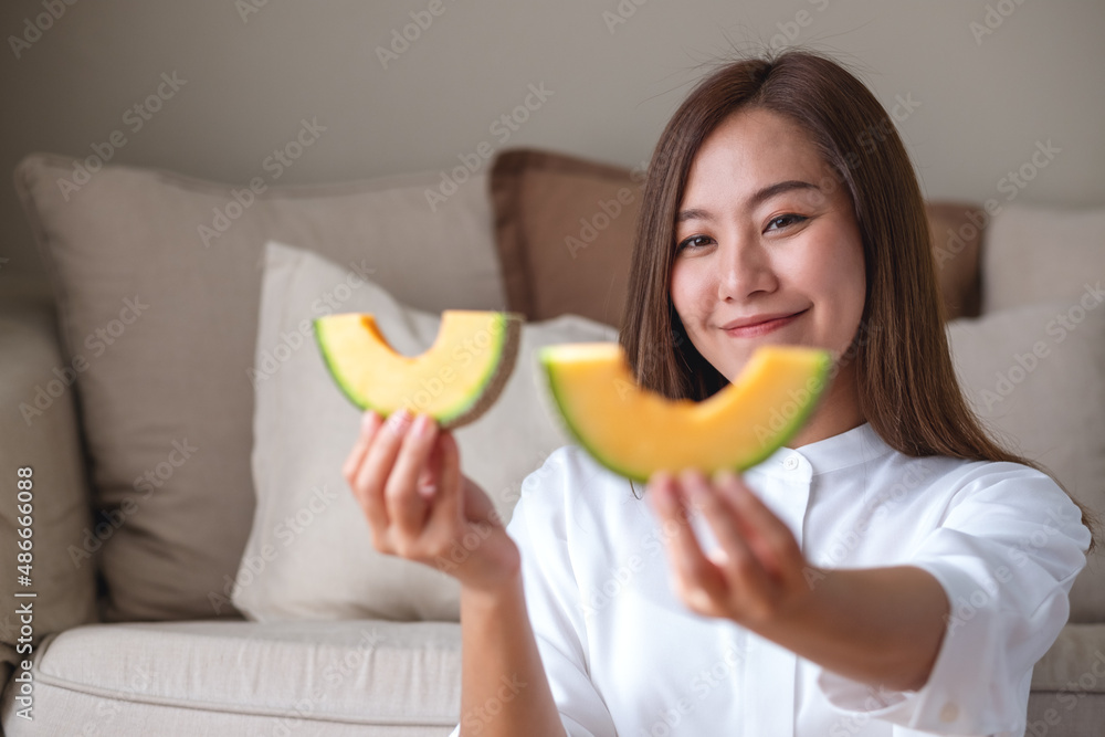 Portrait image of a young woman holding and eating two pieces of Cantaloupe melon Portrait image of a young woman holding and eating two pieces of Cantaloupe melon