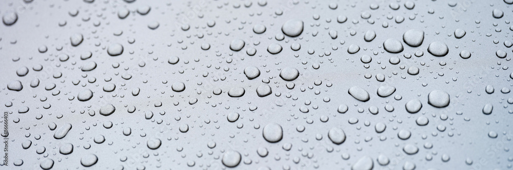 Raindrops on glass against gray sky closeup