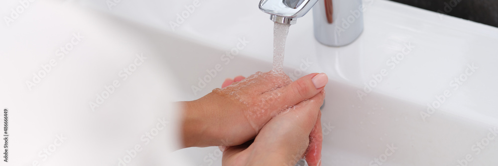 Woman washes hands in cool water in bathroom closeup Woman washes hands in cool water in bathroom closeup