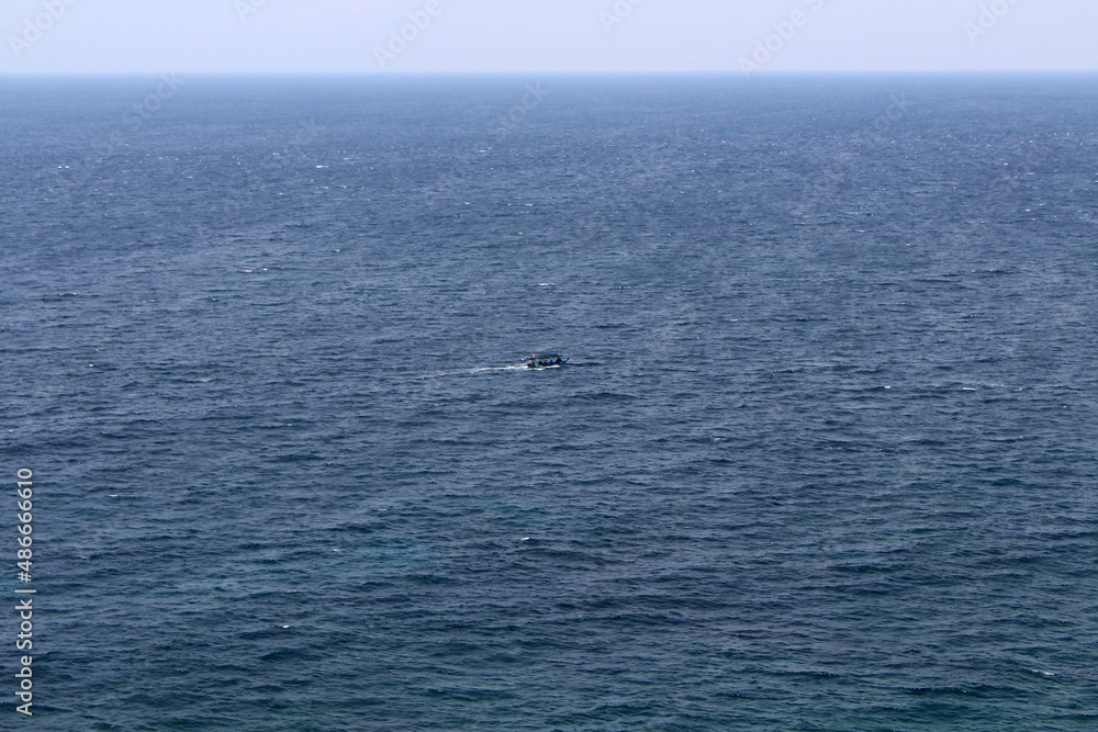 Small boat and horizon line of the Pacific ocean around Uluwatu. Taken January 2022.