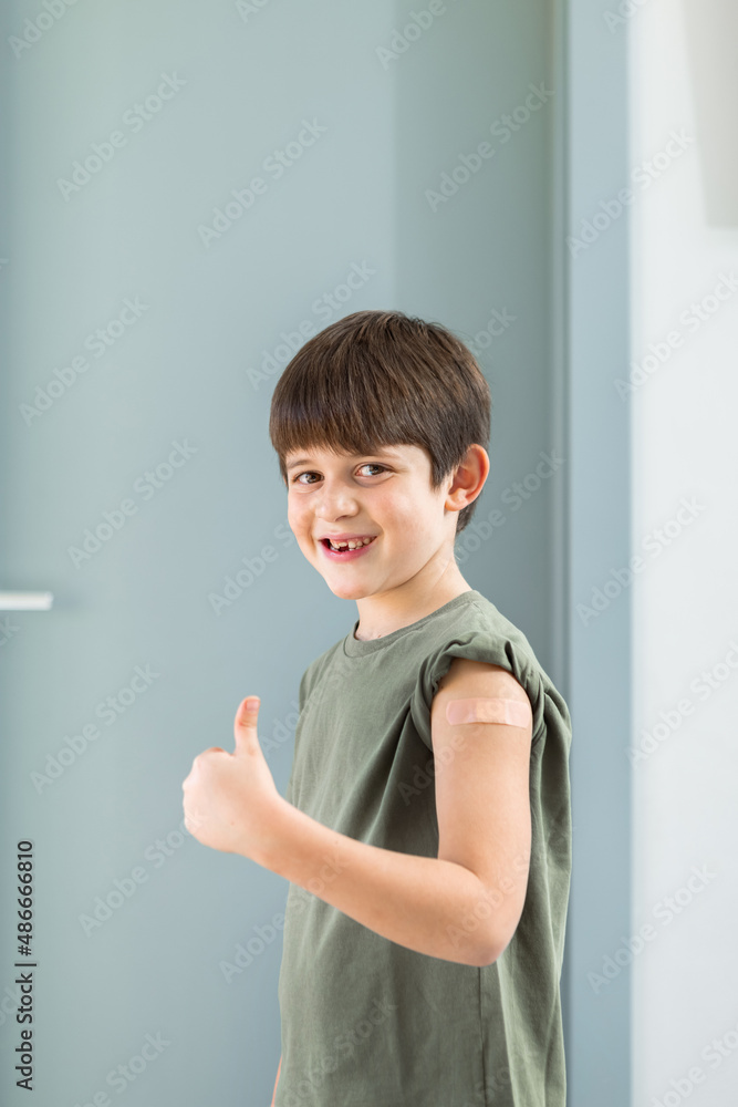 6 year old boy shows plaster stuck on arm to confirm that he got vaccinated. 6 year old boy shows plaster stuck on arm to confirm that he got vaccinated.