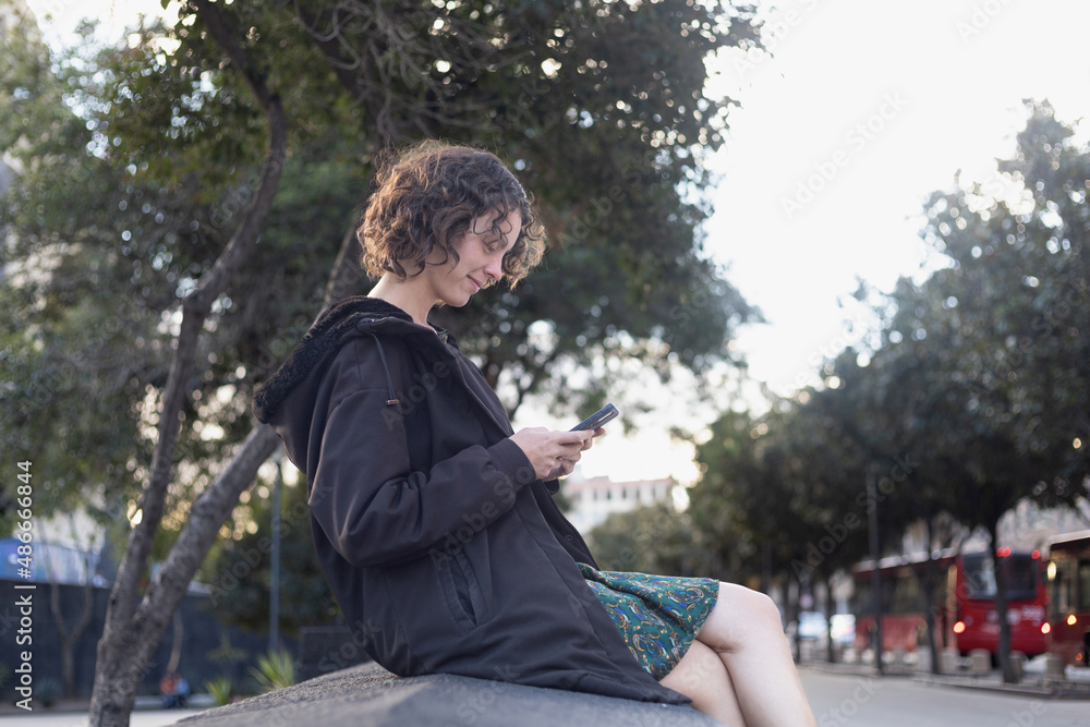 Girl in black coat sitting and looking at her cell phone. Girl in black coat sitting and looking at her cell phone.