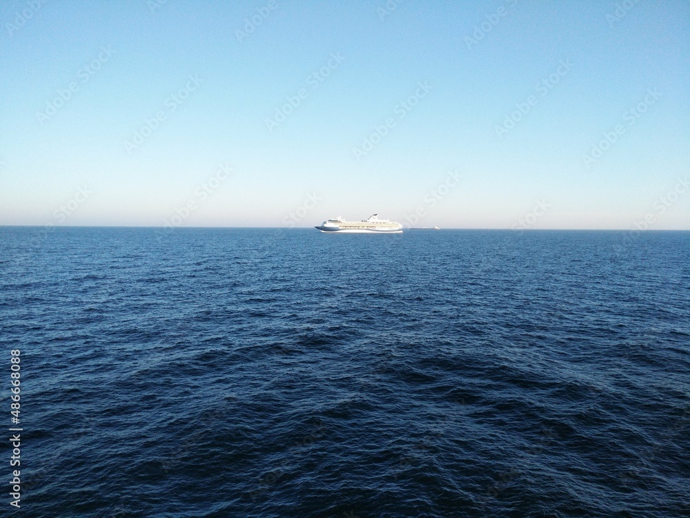 a bright blue sea and a white ship in the distance