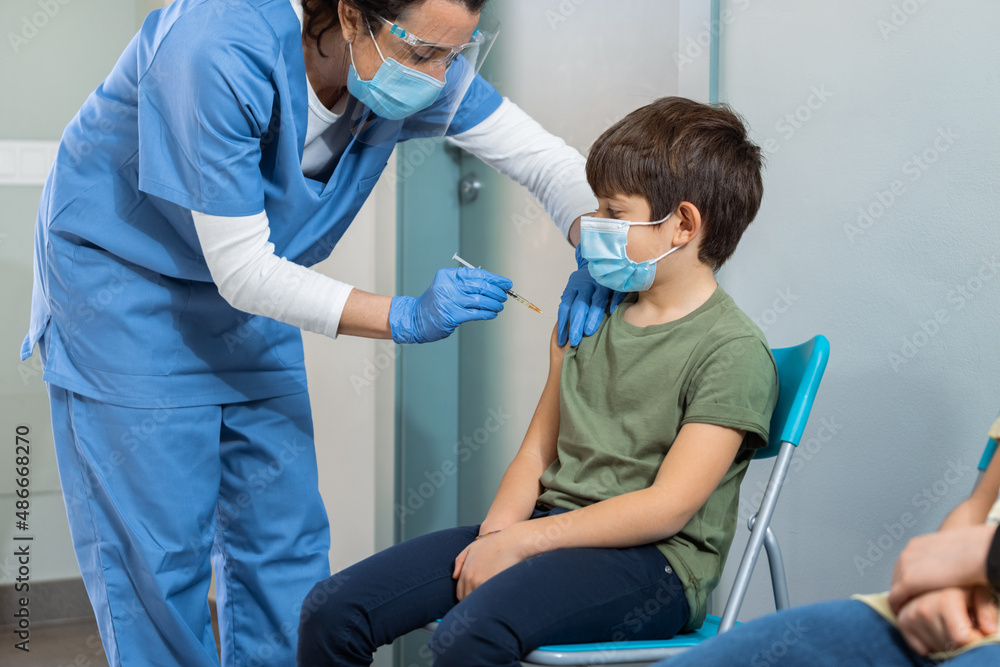 Female doctor giving injection to young boy patient Female doctor giving injection to young boy patient