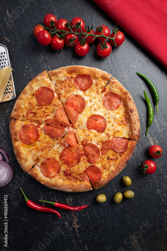 Photos Fresh baked pizza with ingredients on a dark stone table .