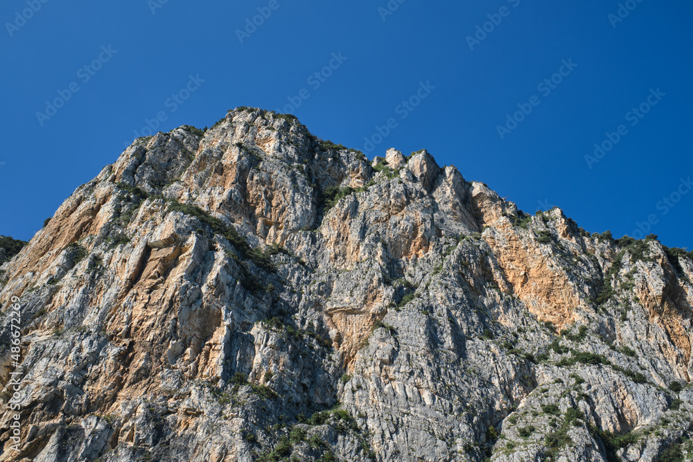 Red stones on a blue background. Alps top on blue sky. Rough rocky stones. The tops of the yellow peaks of the rocks. Gray rocks at high altitude. Red stones on a blue background. Alps top on blue sky. Rough rocky stones. The tops of the yellow peaks of the rocks. Gray rocks at high altitude.
