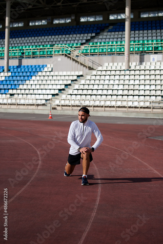 Man stretches the body before running on race track in stadium