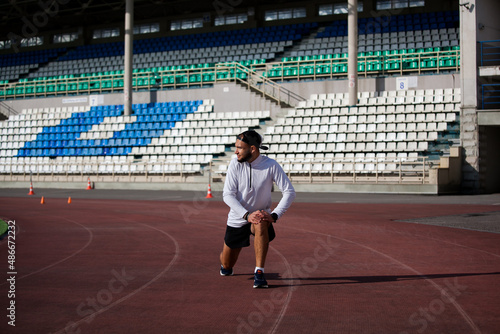 Man stretches the body before running on race track in stadium