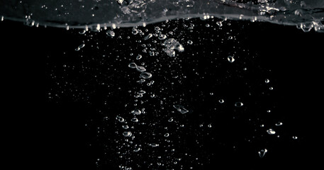 Soda water bubbles splashing and floating drop in black background represent sparkling and refreshing
