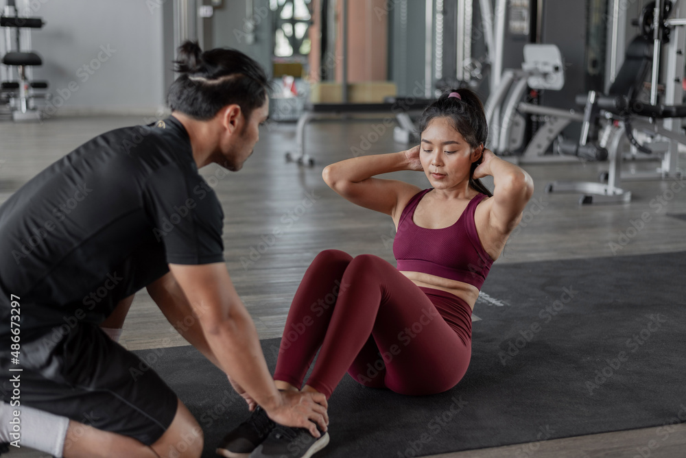 Asian woman exercise with personal trainer in gym. Healthy woman doing abs workout in fitness with personal coach. Asian woman exercise with personal trainer in gym. Healthy woman doing abs workout in fitness with personal coach.