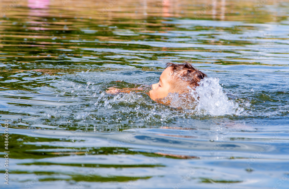 Fototapeta premium the boy bathes in the river, floats on his back