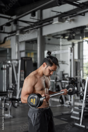 Asian man exercises in fitness. Healthy man doing arms workout in fitness.