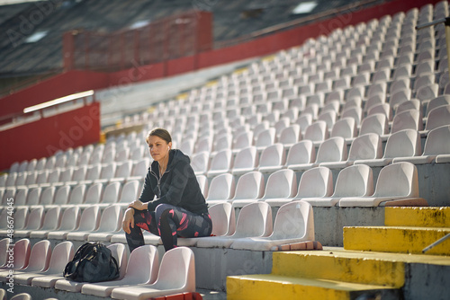A young woman is sitting at the stadium and waiting for a training. Sport, athletics, athletes