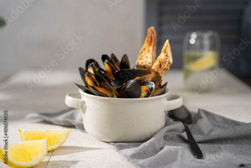 Canvas Print Cooked, boiled mussels with lemon juice, parsley and toasted bread in white bowl (plate) on the table