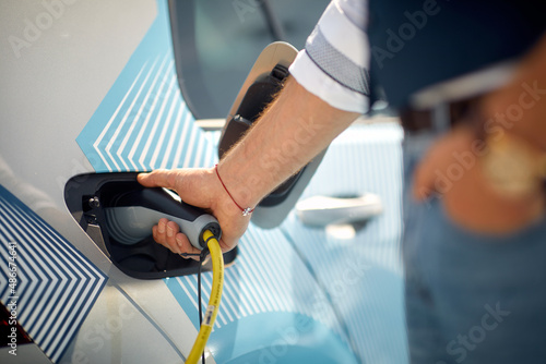 Close-up of a man at the station is plugging in his electric car to a charger. Car, electric, station