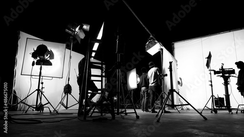 Behind the scenes of TV commercial movie film or video shooting production which crew team and camera man setting up green screen for chroma key technique in big studio.