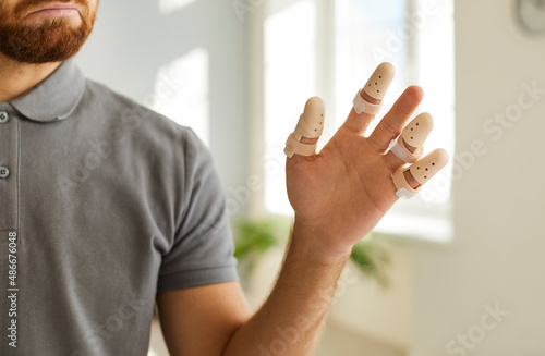 Close up of man's hand wearing adjustable splint braces on injured or broken fingers. Cropped image of man who is forced to wear orthopedic devices to protect against pain or fracture of finger joint.
