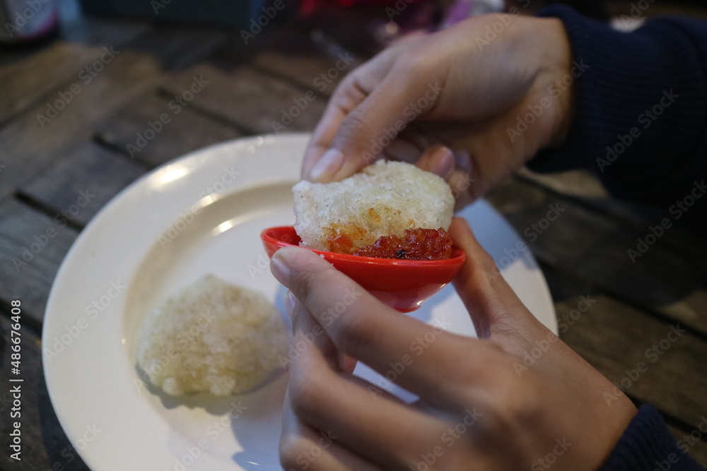 hand holding fried cireng with chili sauce hand holding fried cireng with chili sauce