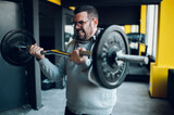 Middle aged man lifting barbell in the gym