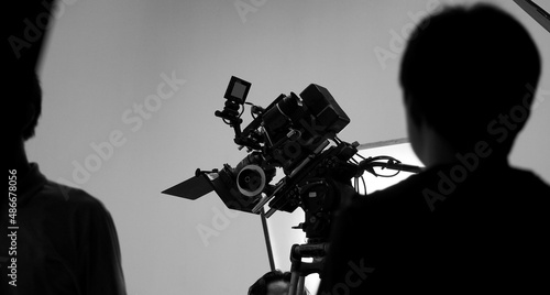 Movie shooting or video filming production by crew team and professional equipment such as super ultra high definition digital camera with tripod and lighting set in studio and black and white styles.