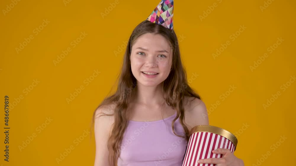 Portrait of a young girl in party con with a gift in her hands celebrating birthday. People lifestyle concept. Portrait of a young girl in party con with a gift in her hands celebrating birthday. People lifestyle concept.