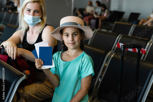 Mother and daughter with face mask going on holiday, at the airport